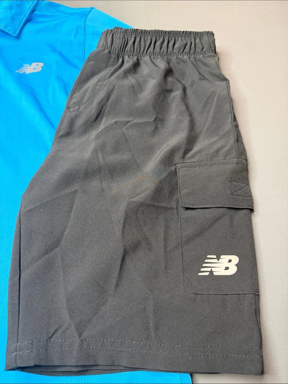 Kid’s New Balance Bright Blue Polo and Black Athletic Shorts Set. Size: 8